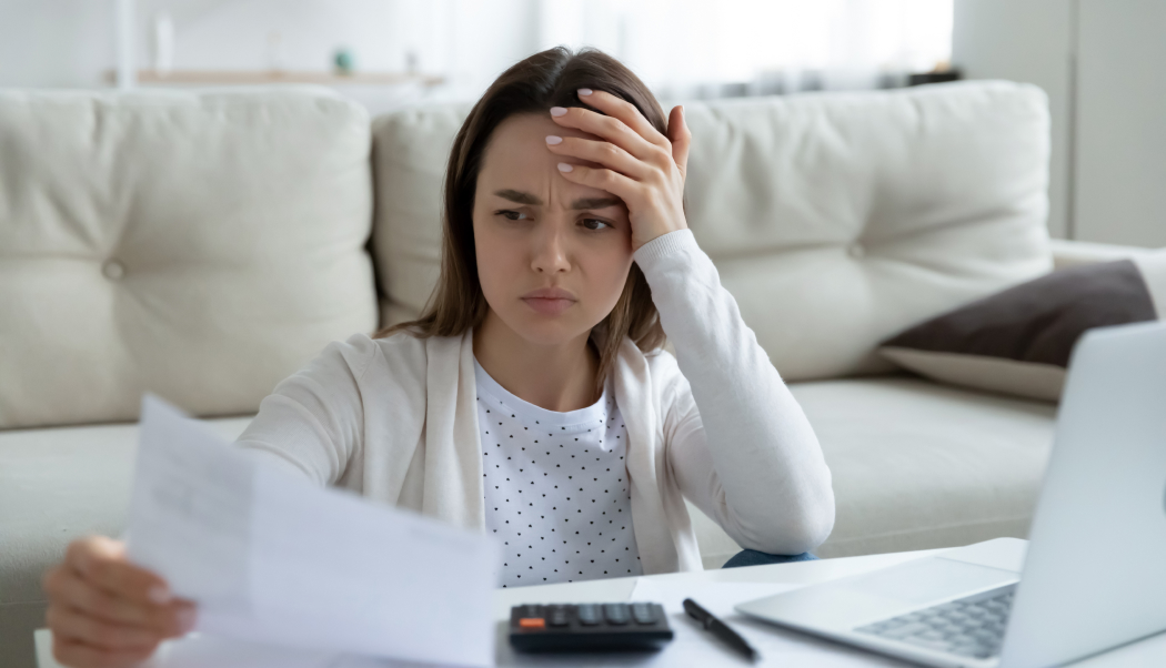 Woman looking at paper worried, holding her hand.