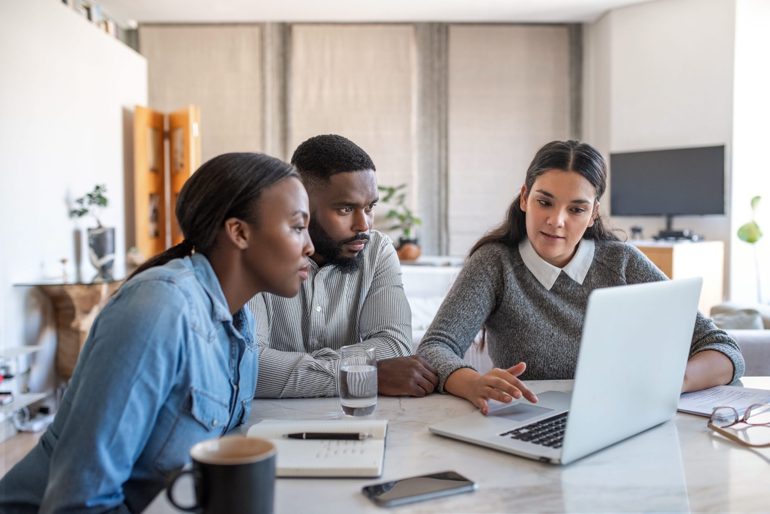 Three people looking at a laptop in an office.